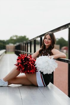 a cheerleader sitting on the ground with her pom poms