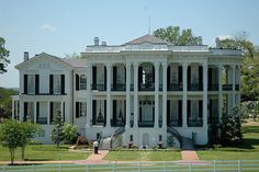 a large white house with black shutters and balconies on the second floor