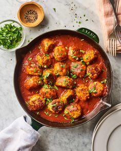 a pan filled with meatballs covered in sauce and garnished with parsley