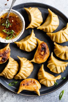 dumplings with dipping sauce on a black plate