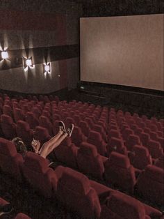 a woman laying on the floor in front of an empty movie theater with red chairs