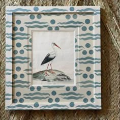 a white and blue bird sitting on top of a piece of paper in a frame