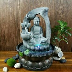 a buddha statue sitting on top of a wooden table next to a potted plant