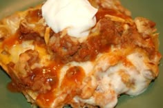 a green plate topped with lasagna covered in sauce and sour crumbles