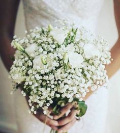 a bride holding a bouquet of white flowers