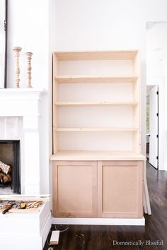 an empty living room with white walls and wooden shelves on either side of the fireplace