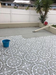 a blue bucket sitting on top of a cement floor next to a fence and palm tree