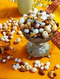 a bowl filled with nuts sitting on top of a yellow table cloth next to a glass vase