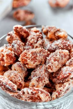 powdered sugar coated donuts in a glass bowl on top of a white table