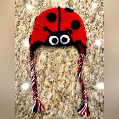 a crocheted ladybug hat with candy canes on it and eyes