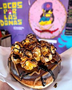 a chocolate covered donut sitting on top of a white paper wrapper in front of a sign