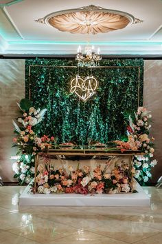 an elegant wedding setup with flowers and greenery on the wall in front of it