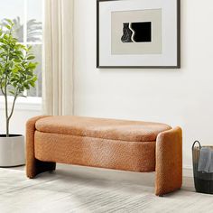 an orange bench sitting in front of a window next to a potted plant