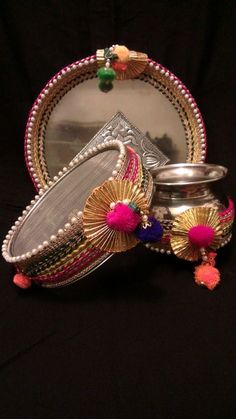 a mirror and some silver items on a black tablecloth with pink tassels