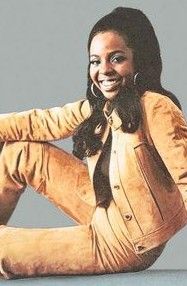 a woman is sitting on the floor with her legs crossed and smiling at the camera