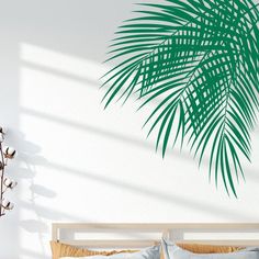 a bedroom with white walls and a green palm leaf wall decal