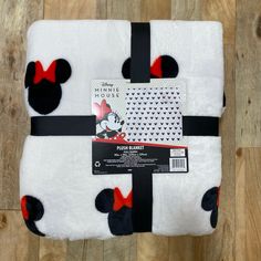 mickey mouse fleece blanket with red and black polka dots on it, sitting on top of a wooden floor