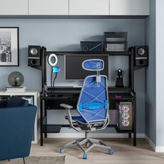 a blue office chair sitting in front of a computer desk with speakers on top of it