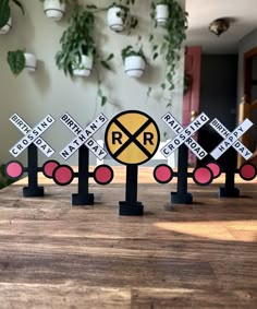 four railroad crossing signs on top of a wooden table in front of a planter