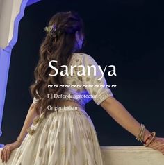 a woman in a white dress standing next to a wall with the words saranya on it