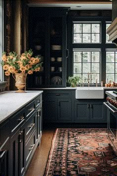 a kitchen with black cabinets and an area rug in front of the sink that has flowers on it