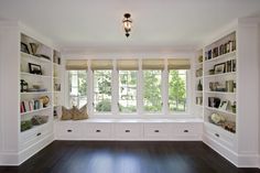 an empty room with white walls and shelves filled with books on the wall, along with a hardwood floor