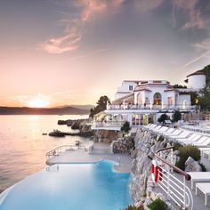 an outdoor swimming pool with chaise lounges next to it and the ocean in the background