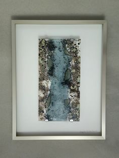 a white frame with a river running through it in front of a gray wall and floor