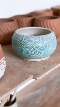 a blue bowl sitting on top of a wooden table next to some brown vases