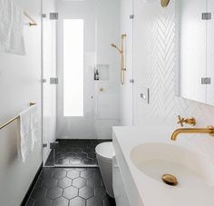 a white bathroom with black and gold accents