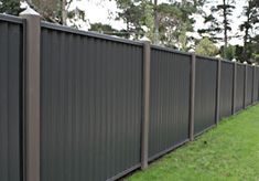 a long black fence in the middle of a green yard