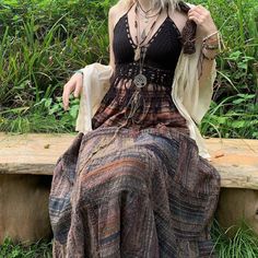 a woman sitting on a wooden bench wearing a dress