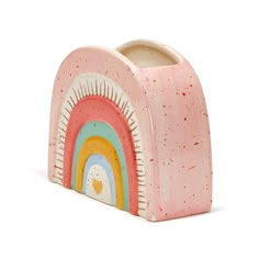 a pink and yellow toothbrush holder with a rainbow design on the front, against a white background