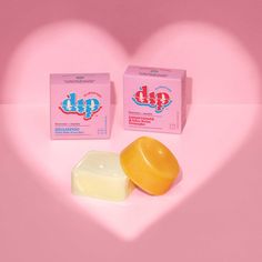 two soaps in the shape of a heart and a box of dip on a pink background