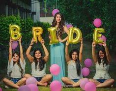 a group of women sitting on the ground holding up balloons