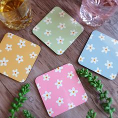 four coasters with flower designs on them sitting next to a glass of water and some green leaves