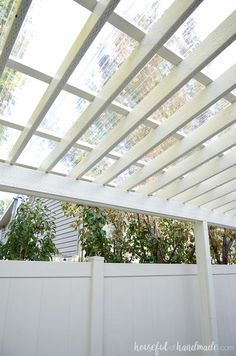 a man is standing under a pergolated roof in front of a white fence