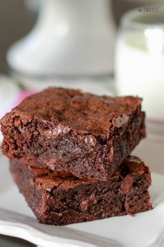 two pieces of chocolate brownie sitting on top of a wooden table next to an avocado