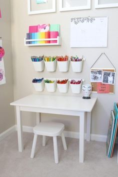 a white table topped with lots of cups filled with crayons