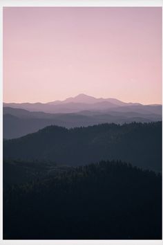 the mountains are covered with trees at sunset