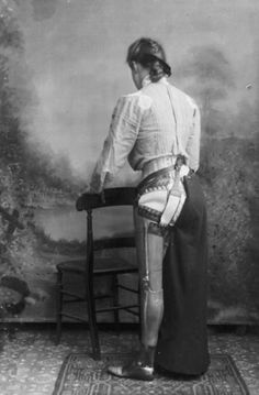 an old photo of a woman standing in front of a chair with her back to the camera