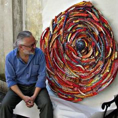 a man sitting next to a large piece of art