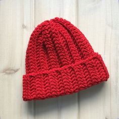 a red knitted hat sitting on top of a wooden table