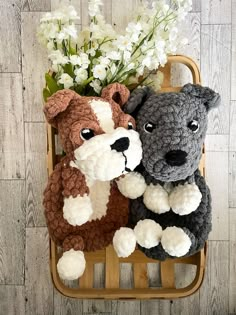 two crocheted stuffed dogs sitting next to each other on a chair with flowers in the background