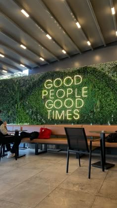 people sitting at tables in front of a green wall with the words good people good times written on it