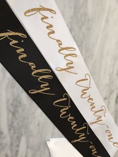 two black and white sashes with gold writing on them, one for the bride and one for the groom