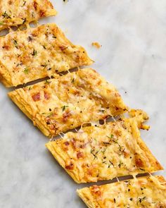 several slices of pizza sitting on top of a white counter next to a fork and knife