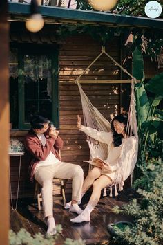 two people sitting in a hammock on a porch with one person taking a photo