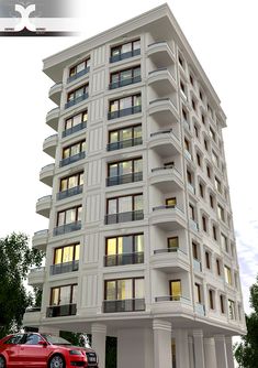 a red car is parked in front of a tall white building with balconies