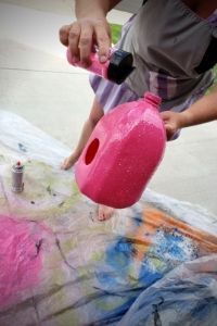 a man is painting with pink paint on the ground and holding a spray bottle in his hand